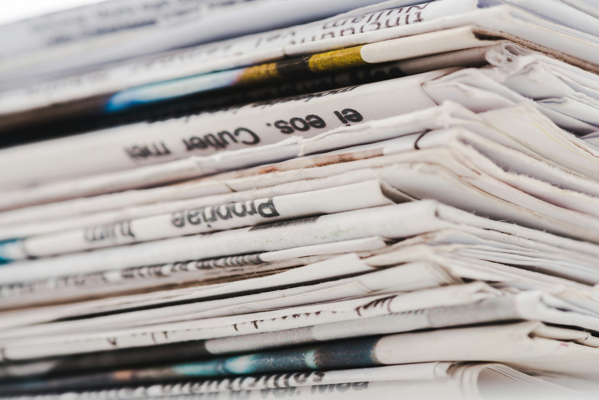 close up of different print daily newspapers in stack